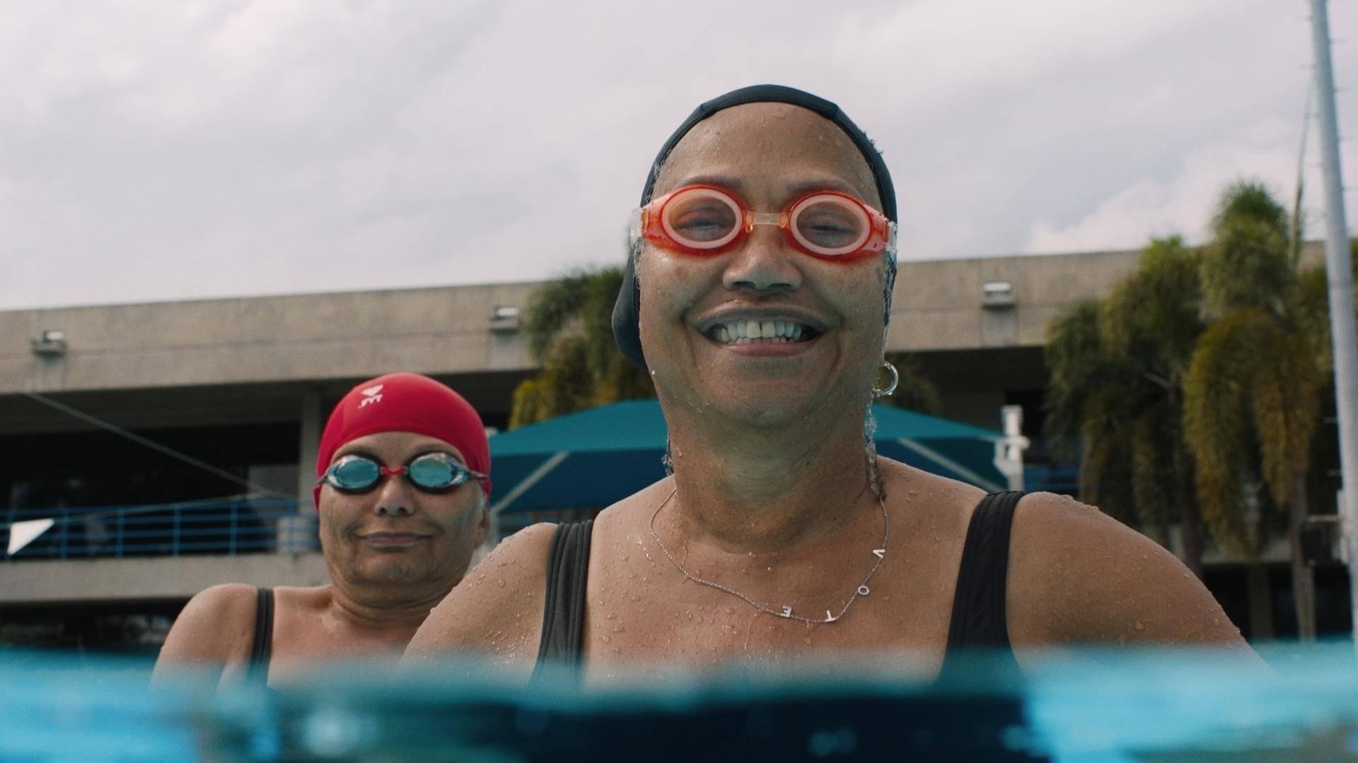 两个上了年纪的女人戴着泳镜和泳帽在泳池里
